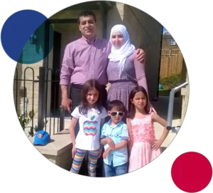 A proud Muslim family of five standing together outside their new home.