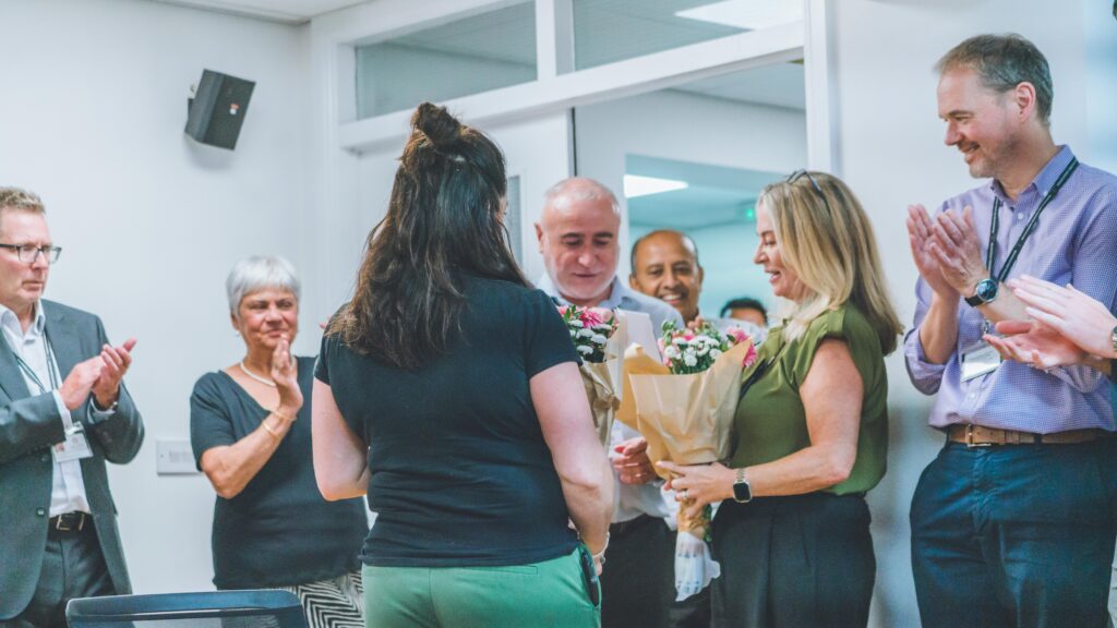 A group of staff celebrating and presenting flowers for reopening of Bank House following refurbishment